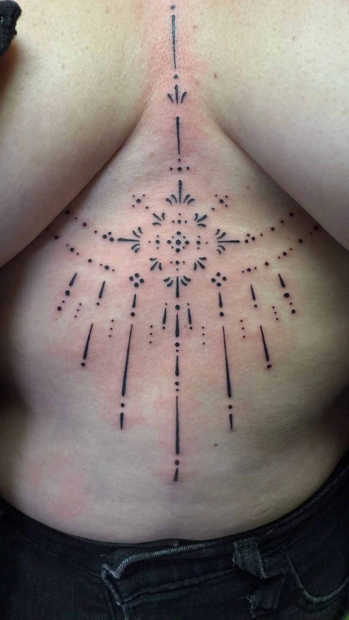 Fine-line ornamental chest tattoo